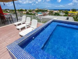 科苏梅尔Hotel Pal Cozumel的阳台旁设有游泳池,旁边设有白色椅子