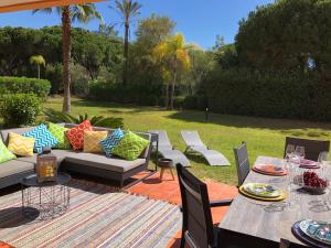 eine Terrasse mit einem Sofa, Tischen und Stühlen in der Unterkunft Casa de Férias Vila Sol Golf in Quarteira