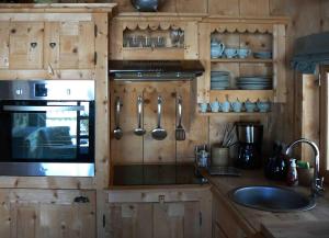 a kitchen with wooden cabinets and a sink and a stove at Le Grenier à Luge in Les Gets