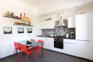 a kitchen with white cabinets and a table with red chairs at Galeria Home Apartments in Anguillara Sabazia