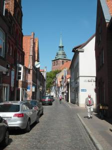 Um velho está a andar por uma rua de calçada. em ALTSTADTGLÜCK - inklusive Privatparkplatz! em Lüneburg