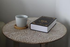 a table with a cup and a book and a coffee mug at The Best Atlantic Ocean View in Câmara de Lobos