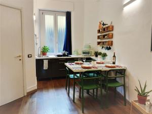 Beautiful Open-Space Loft في ميلانو: مطبخ مع طاولة مع كراسي خضراء وكاونتر