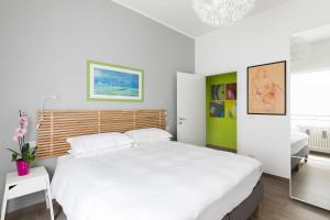 a white bedroom with a large bed and a mirror at Galeria Home Apartments in Anguillara Sabazia