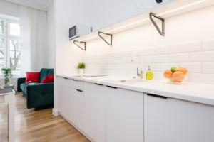uma cozinha com armários brancos e um sofá verde em Old Time Apartments em Cracóvia