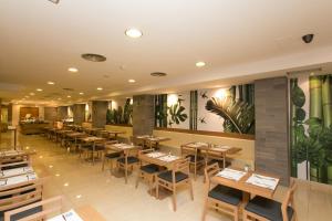 un restaurante con mesas de madera, sillas y plantas en las paredes en Hotel Don Pepe - Adults Only, en El Arenal