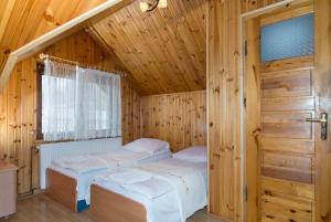 two beds in a wooden room with a door at Gościniec Basia in Kazimierz Dolny