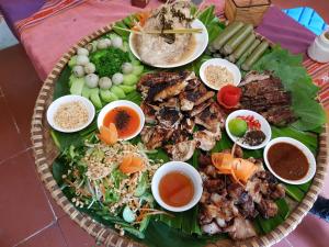 a plate of food with meat and vegetables and dipping sauces at Mai Chau Home in Mai Châu