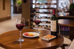 Hotel Fioreze Primo في غرامادو: طاولة خشبية مع كأسين من النبيذ والطعام