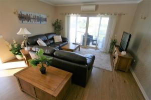 a living room with a black leather couch and a table at Alvor Retreat at Vila Marachique in Alvor