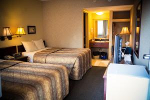 a hotel room with two beds and a television at Langley Hwy Hotel in Langley