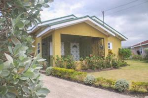 a small yellow house with flowers in the yard at Hibiscus Villa @ DraxHall in Mammee Bay