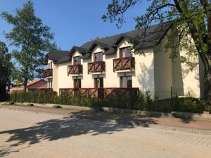 a white house with a black roof and a fence at Dom Wypoczynkowy Sztorm in Ostrowo