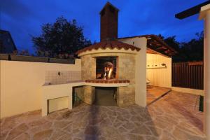 an outdoor fireplace in a backyard at night at Villa Arancia in Kožino