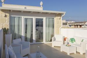 un patio con sedie bianche e tavoli sul balcone di Petra Bianca a Torre San Giovanni Ugento