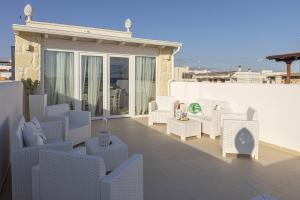 a patio with white chairs and tables on a building at Petra Bianca in Torre San Giovanni Ugento