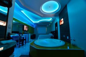 uma casa de banho com uma grande banheira num quarto com luzes azuis em Amy Motel em Blumenau