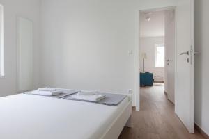 Apartments Coast 27 في بودغورا: غرفة نوم بيضاء مع سرير عليه مناشف