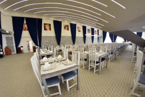 a dining room with white tables and white chairs at Hotel Victoria in Mamaia