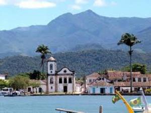 ein Gebäude mit einem Uhrturm neben einem Wasserkörper in der Unterkunft Casa Azul in Paraty