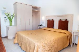 een slaapkamer met een groot bed met een gele sprei bij Hotel Nettuno in Caorle