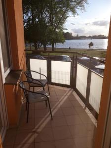 a balcony with two chairs and a view of the water at Tila in Wałcz