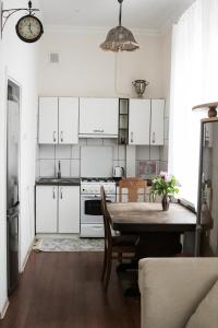 eine Küche mit weißen Schränken und einem Tisch mit Stühlen in der Unterkunft Vintage Style spacious apartment in Klaipėda