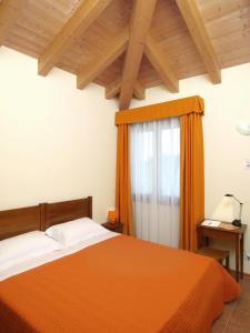 1 dormitorio con cama de color naranja y ventana en Agriturismo Ai Laghi, en Pocenia