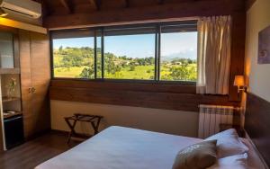 a bedroom with a bed and a large window at La Casona de Abamia in Corao