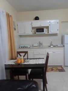 cocina con mesa, sillas y microondas en Barrianna Villa en Montego Bay