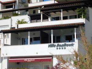 a white building with a white bathroom sign on it at Beach Villa Bozikovic in Podstrana