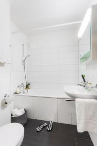 a white bathroom with a tub and a sink at Swiss Star Zurich Sihlfeld - Self Check-In in Zürich