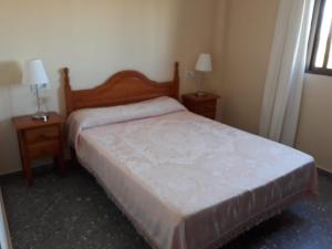 ein Schlafzimmer mit einem Bett mit zwei Nachttischen und zwei Lampen in der Unterkunft Vivienda Rural Alcazaba in Chipiona