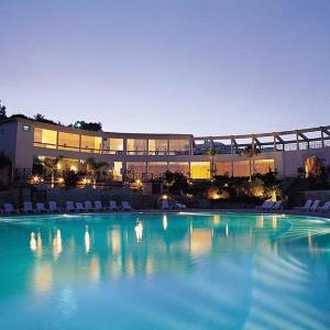 een groot zwembad met stoelen en een gebouw bij Quinta da Floresta – Santo António Villas, Golf & Spa in Budens