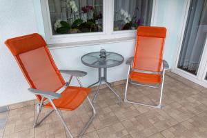 duas cadeiras laranja e uma mesa de vidro num quarto em Orchid room em Kranj