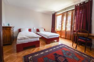 a bedroom with two beds and a desk and a rug at Magnifique maison vigneronne avec grand jardin in Auvernier
