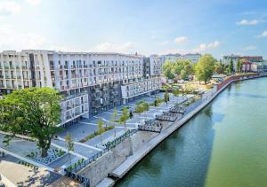 budynek obok rzeki z drzewami i budynkami w obiekcie About Art Apartments - Sikorskiego we Wrocławiu