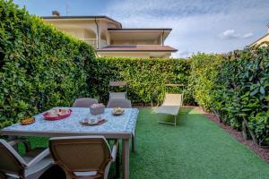 a patio with a table and chairs in front of a hedge at Casa Francesca in Sirmione