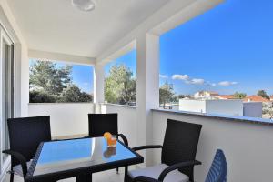 einen Balkon mit einem Tisch, Stühlen und Fenstern in der Unterkunft Apartments Mica in Vrsi