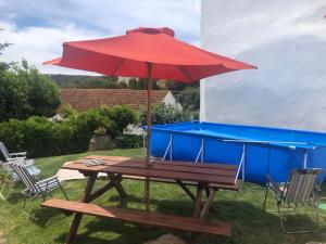 a picnic table with a red umbrella on the grass at Casa da Palmeira in Outeiro da Cortiçada