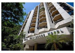 a tall white apartment building with palm trees in front of it at Apart hotel Copacabana Próximo a praia in Rio de Janeiro