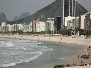 a beach with people in the water and buildings at Apart hotel Copacabana Próximo a praia in Rio de Janeiro