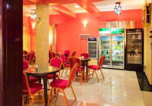 a restaurant with tables and red chairs and a drink cooler at Sibyangu Standard Hotel Kampala in Kampala