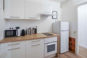 a kitchen with white cabinets and a white refrigerator at NOCNOC - La Comédie in Montpellier