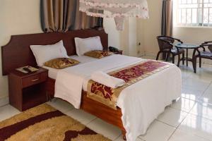 a bedroom with a large bed and a table at Sunrise Hotel Kampala in Kampala