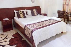 a bedroom with a large bed with a wooden headboard at Sunrise Hotel Kampala in Kampala
