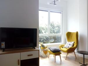 a living room with a flat screen tv and two yellow chairs at Apartamento Donostia Chic in San Sebastián