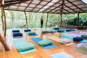 una mujer parada en una habitación con un montón de esterillas de yoga en Mystica, en Naranjos Agrios