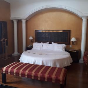 a bedroom with a large white bed and a bench at Villas Princess Hotel in Mexico City