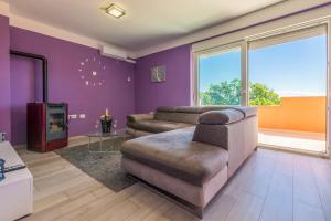 a living room with purple walls and a couch at Apartmani Vesna in Opric